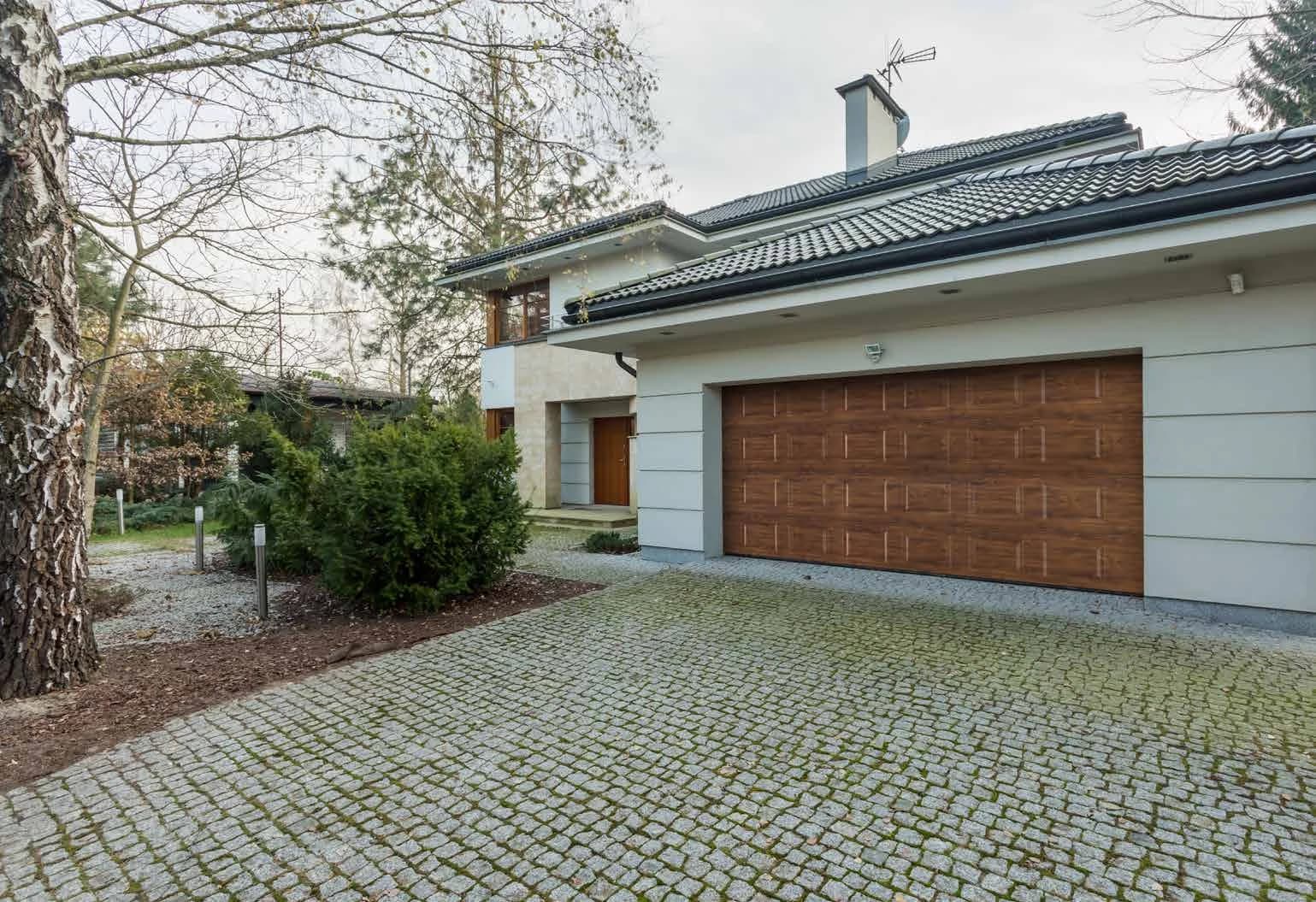 Porte de garage sectionnelle à cassettes, finition bois, sur une maison à toit de tuiles