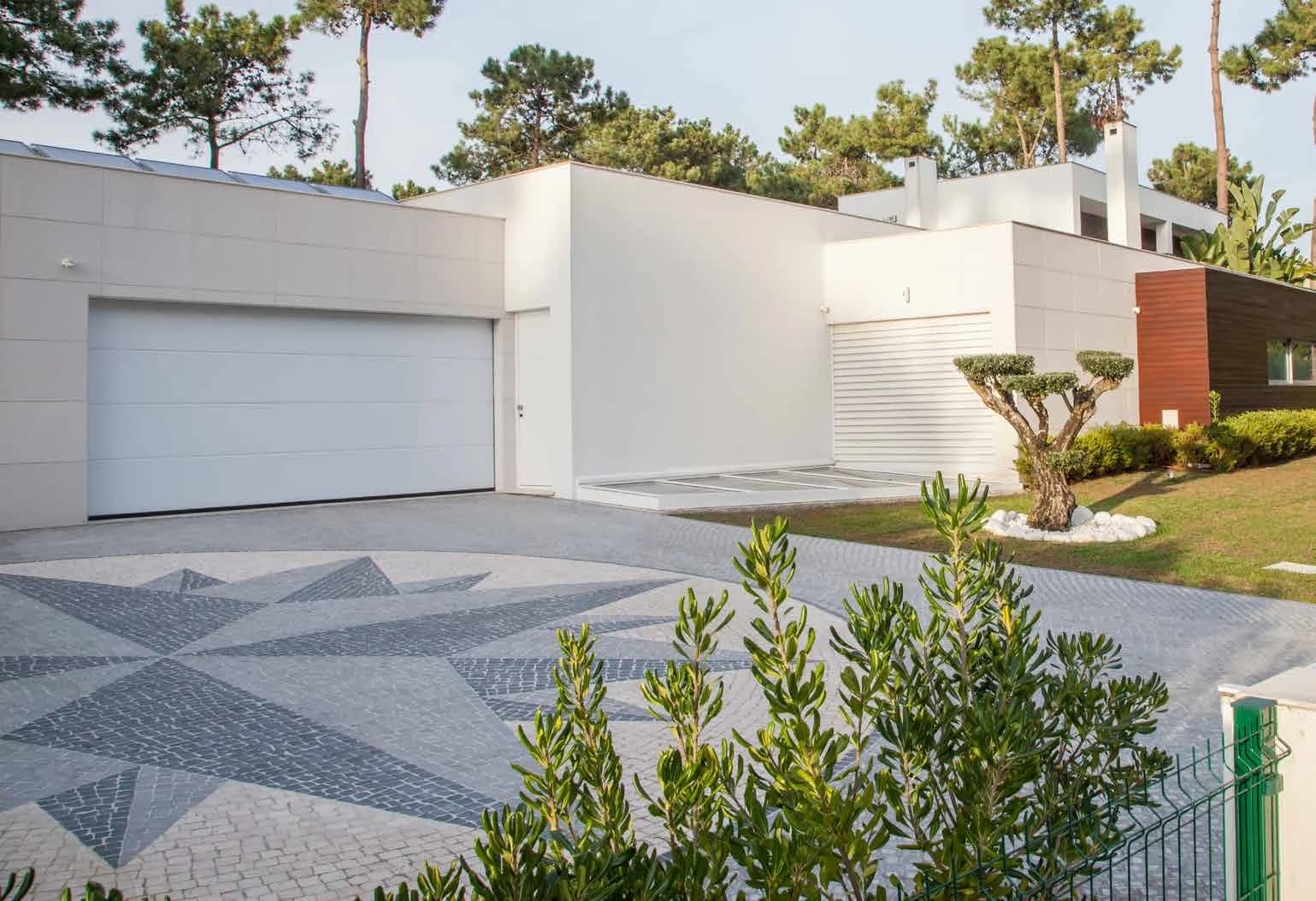 Porte de garage sectionnelle blanche à panneaux lisses sur une maison contemporaine