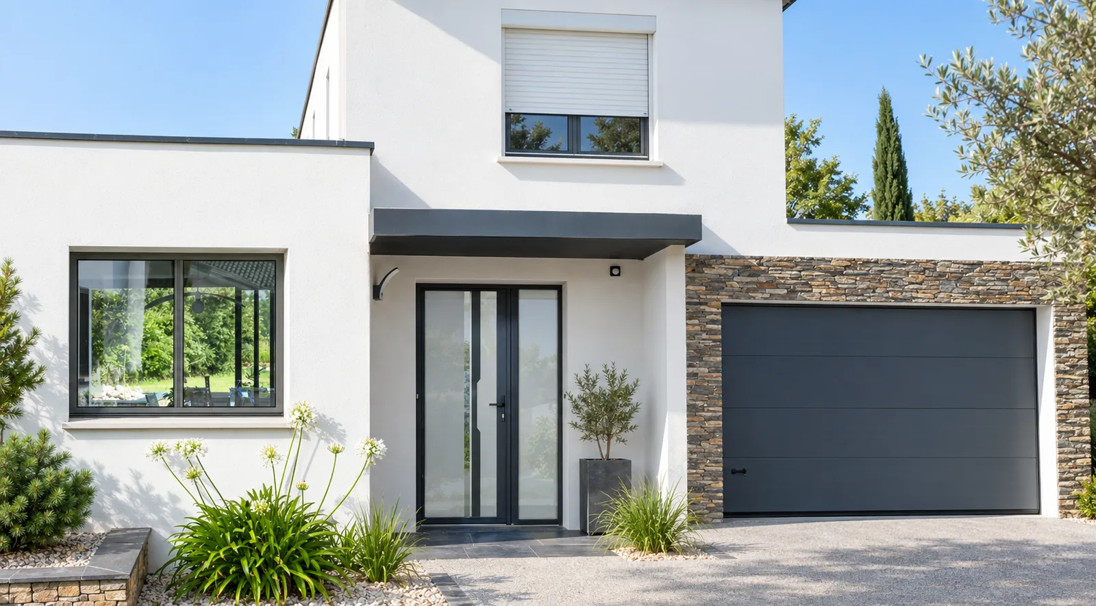 Maison contemporaine blanche avec fenêtre aluminium anthracite, porte d’entrée vitrée sous auvent, volet roulant blanc à l’étage et porte de garage sectionnelle anthracite