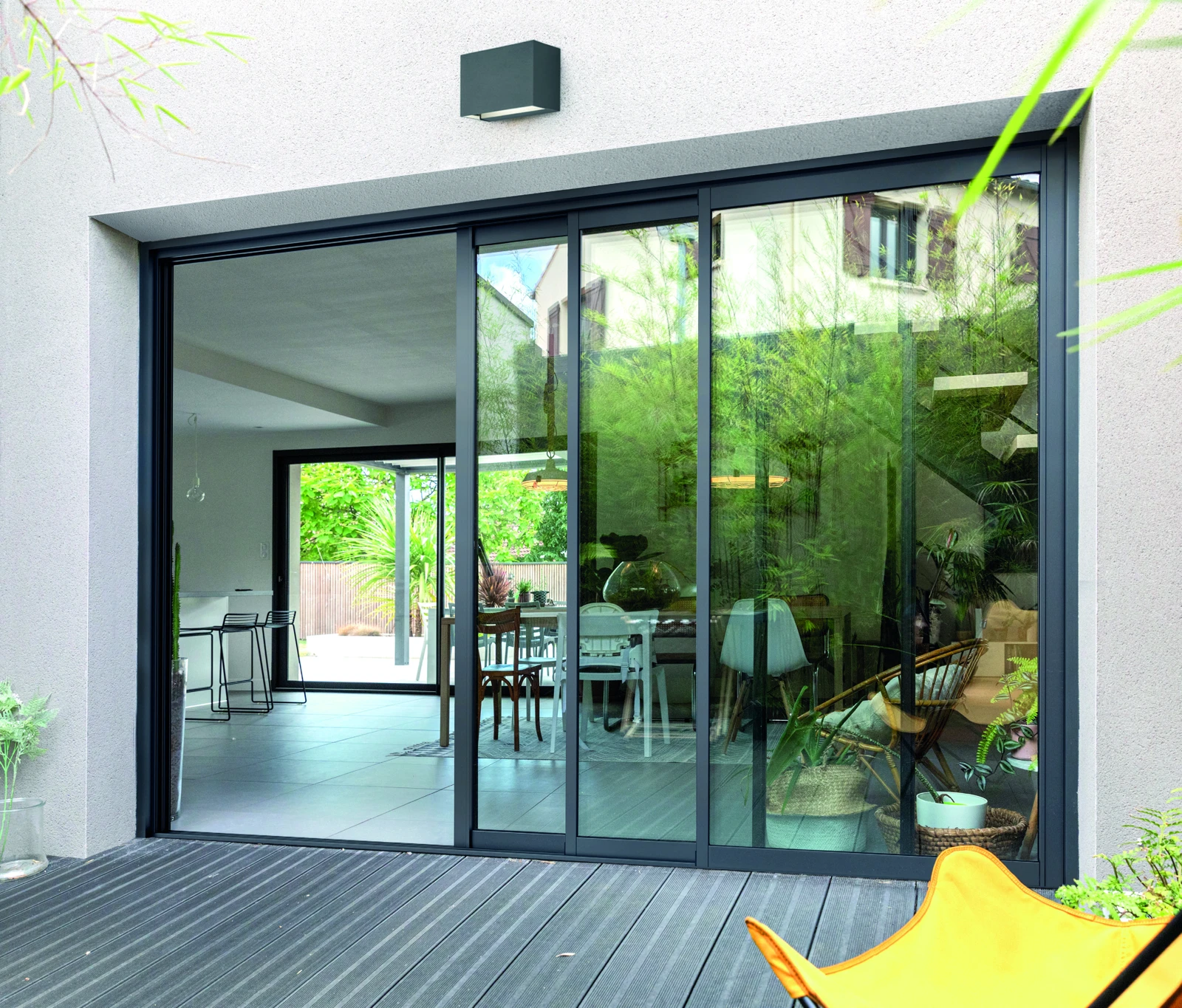Baie aluminium coulissante ouverte sur une terrasse, vue extérieure complète
