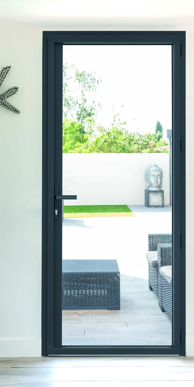 Porte-fenêtre aluminium gris foncé à un vantail, vue de l’intérieur, donnant sur une terrasse
