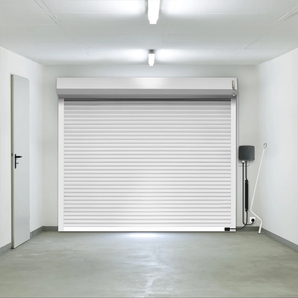 Porte de garage enroulable blanche vue de l’intérieur : coffre, coulisses, boîtier de commande et manivelle de secours visibles