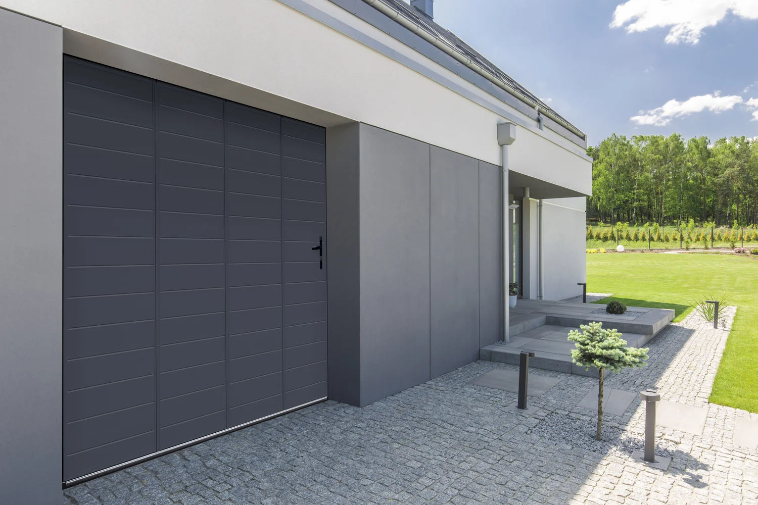 Porte de garage coulissante aluminium sombre avec passage piéton dans une façade contemporaine